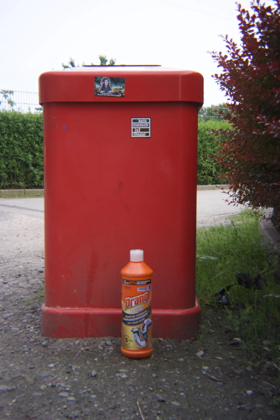 a trashcan with pipe cleaner in front, theres also a sticker that says "no person is illegal"